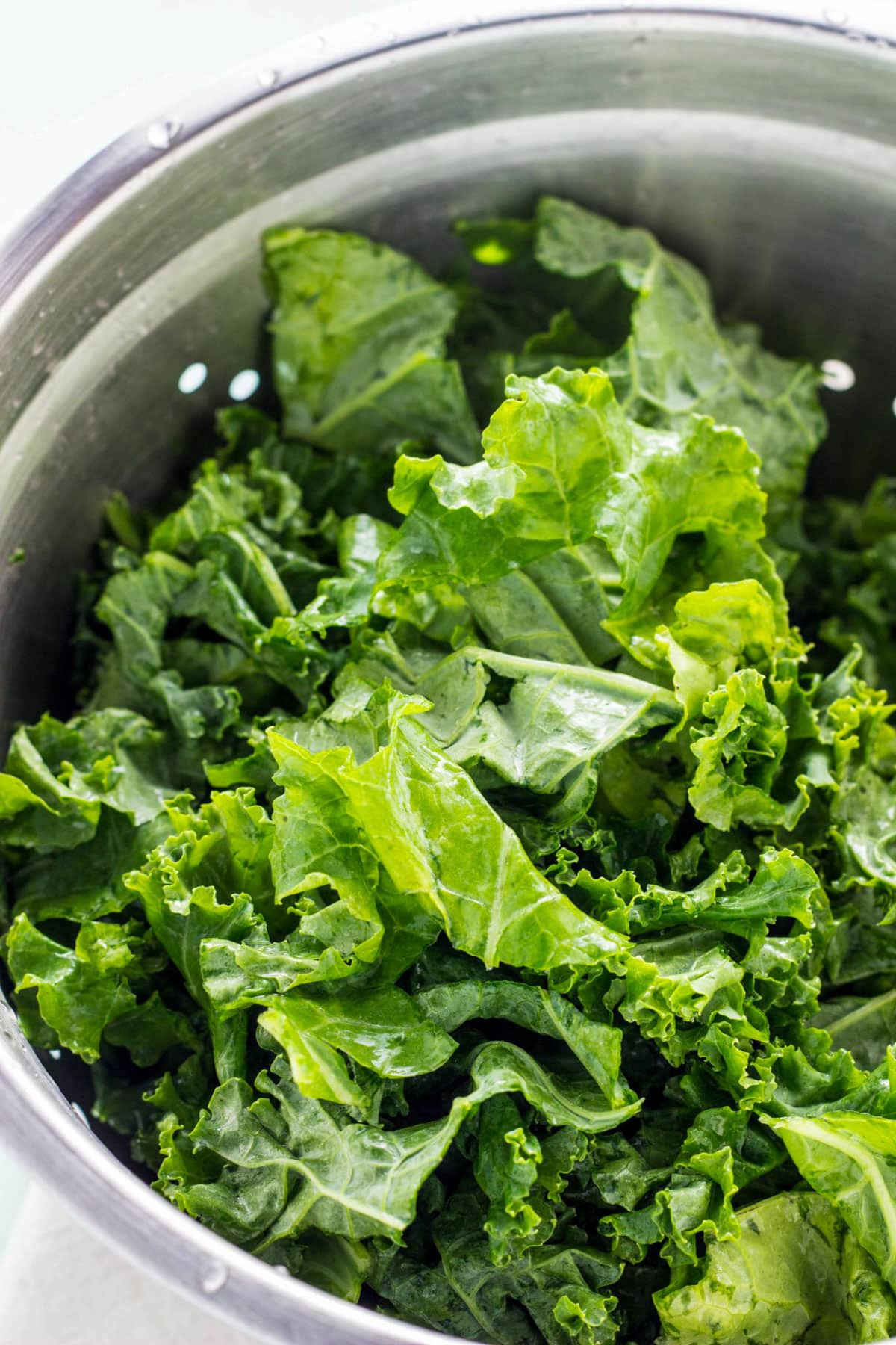 Close up of a colander of torn pieces of kale.