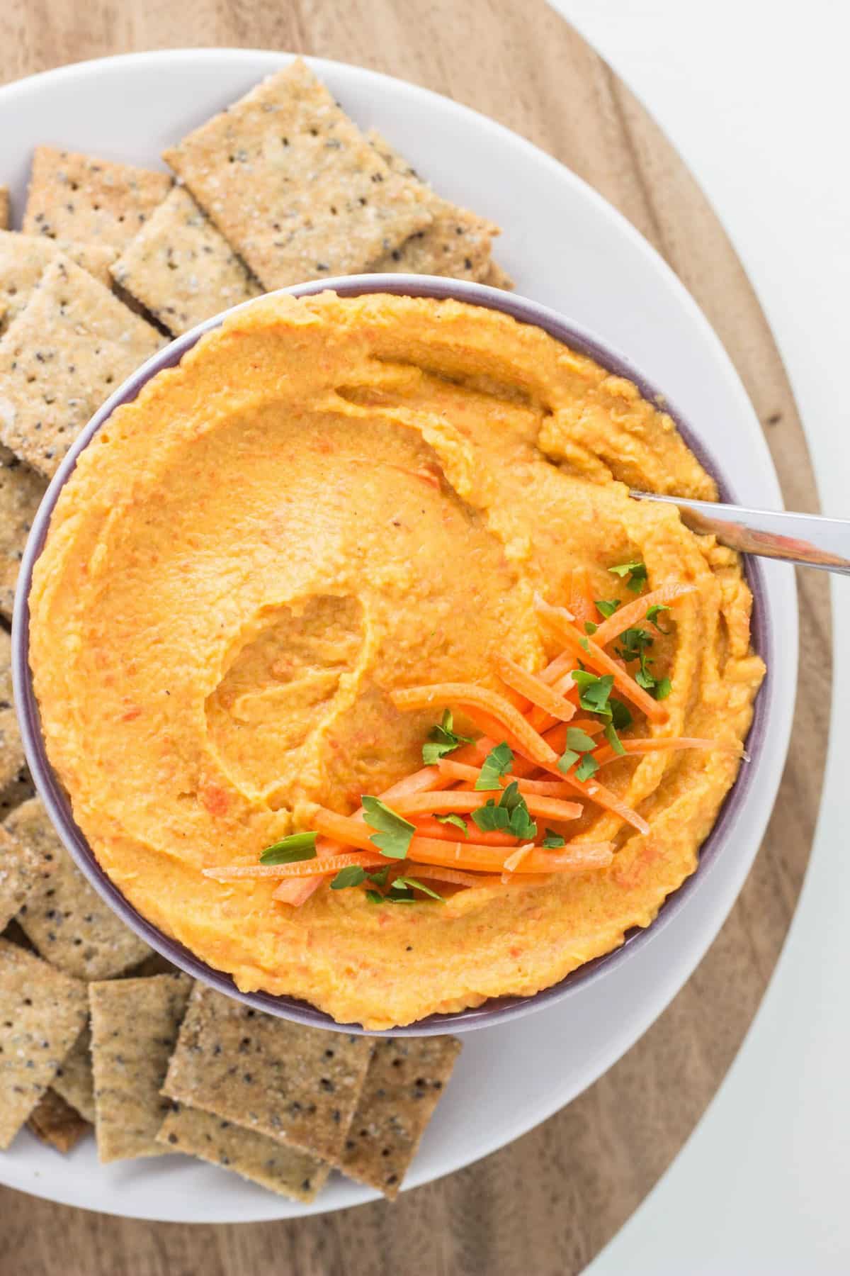 Overhead view of Roasted Carrot Garlic White Bean Dip. There are carrots next to the bowl.