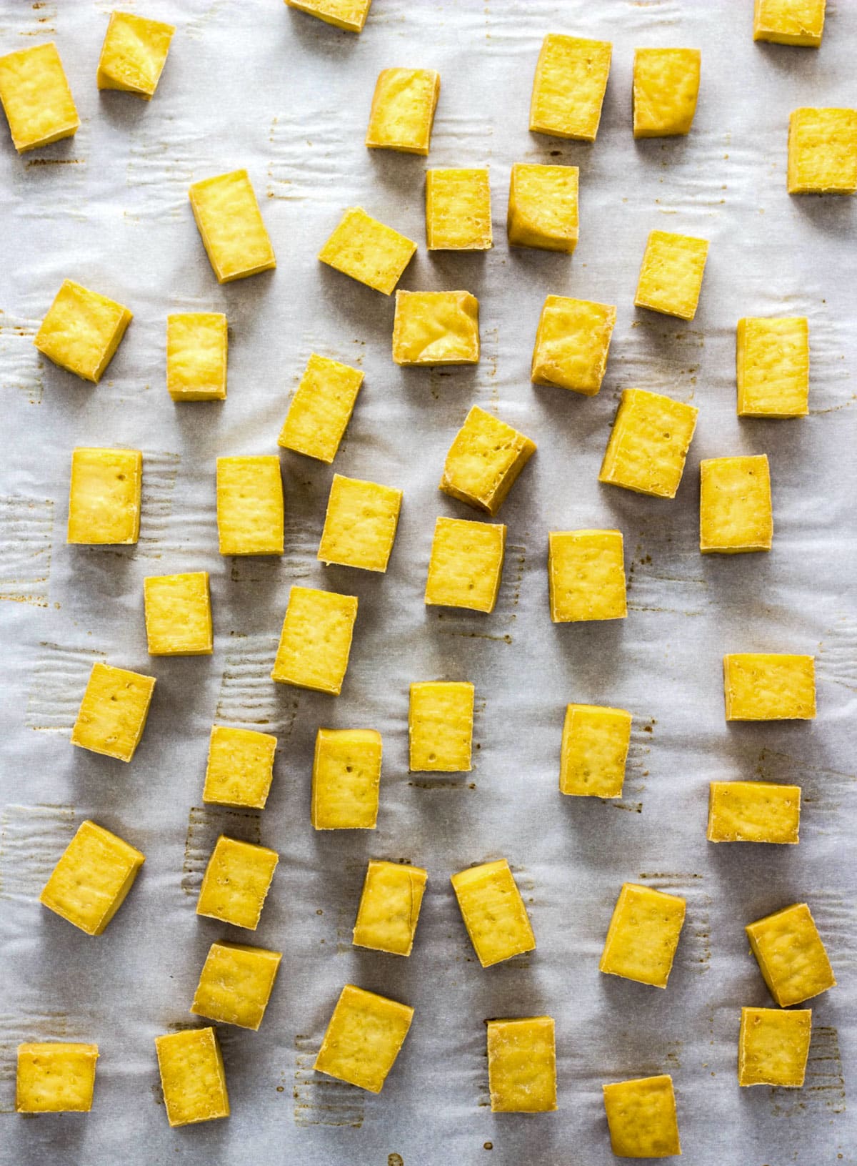 Baked tofu squares on a baking sheet lined with parchment paper.
