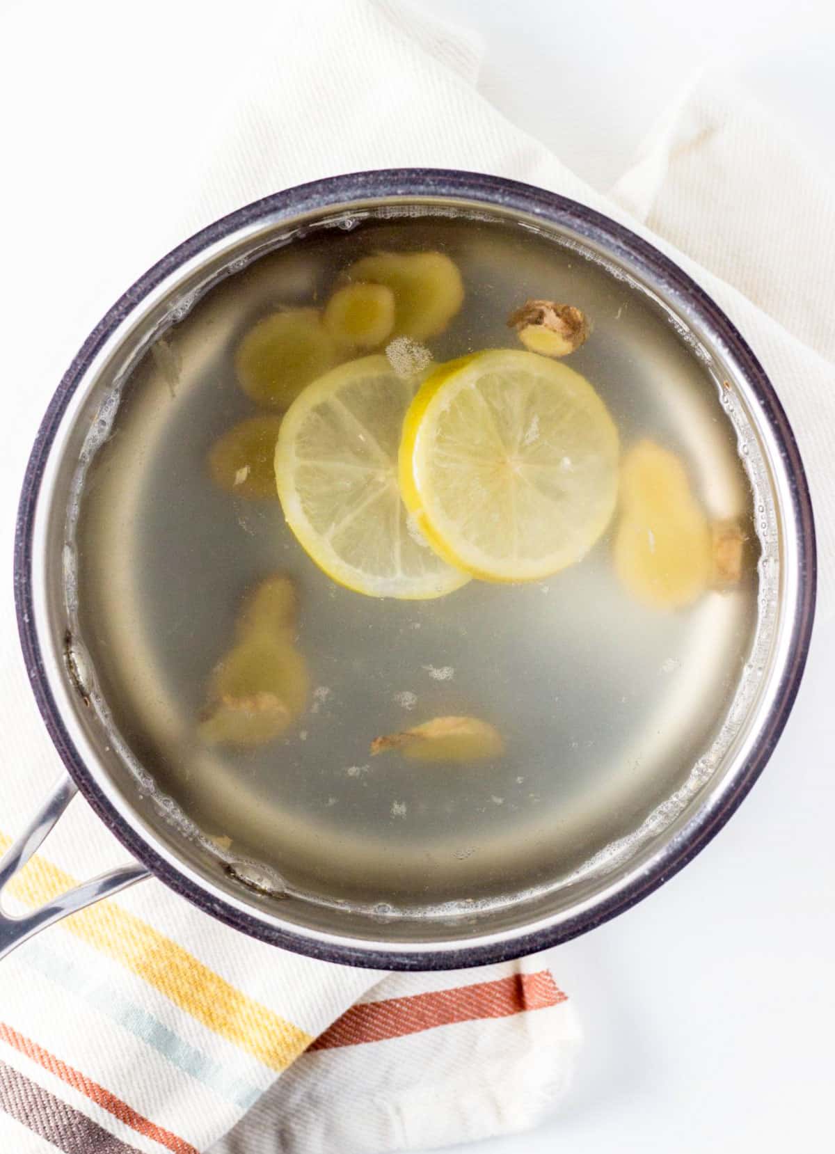 A small pot with Soothing Ginger Lemon Tea made with fresh ginger, lemon slices and water.