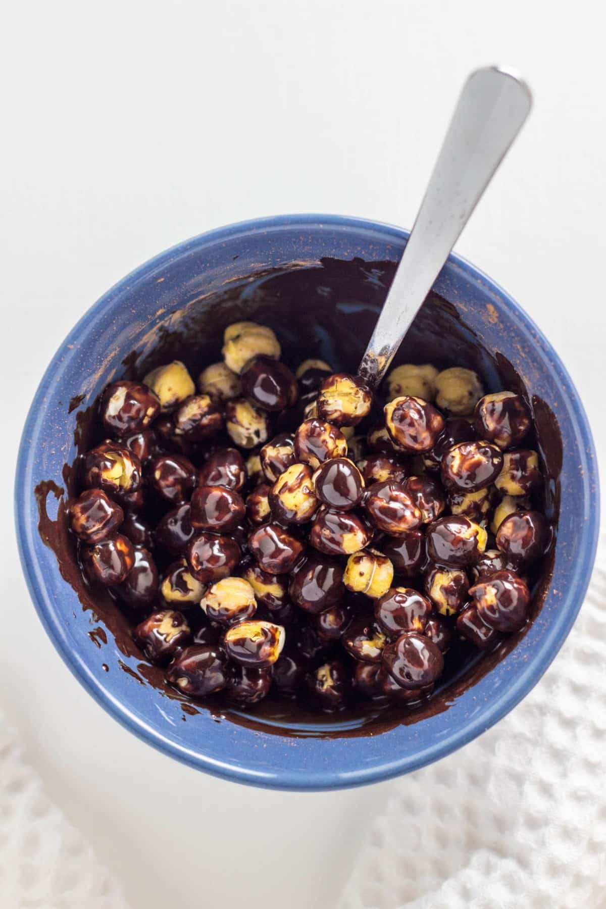 Roasted chickpeas partially coated in chocolate in a small blue bowl.