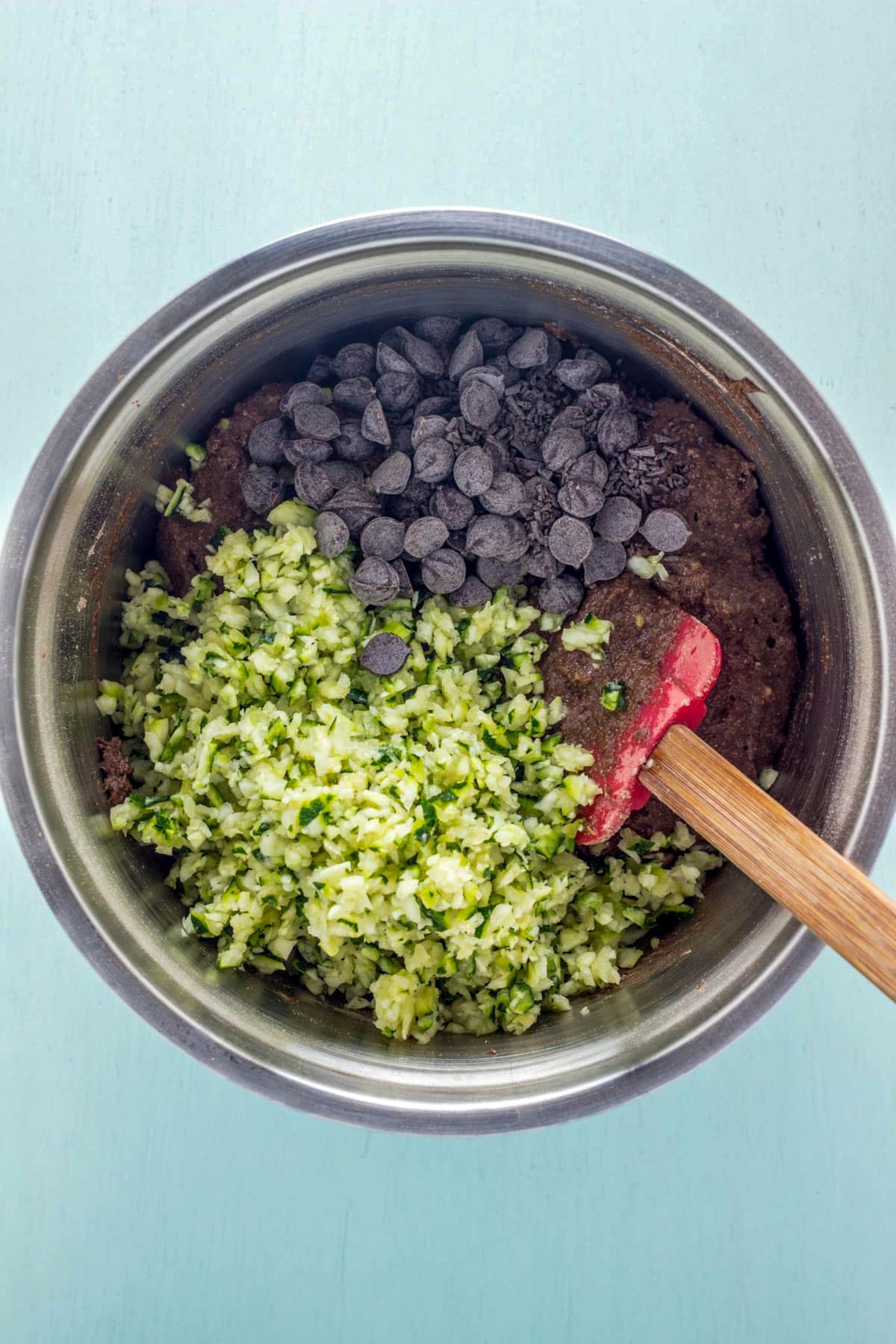 A bowl of batter with shredded zucchini and chocolate chips before combining.