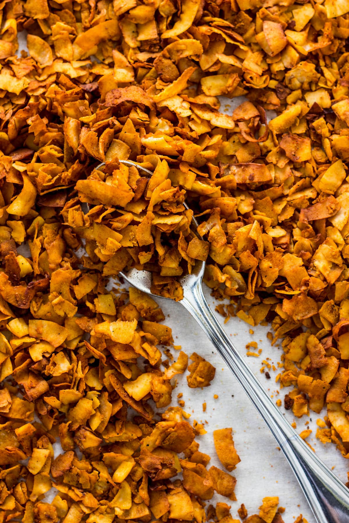 Coconut Bacon on a sheet pan with a spoon.