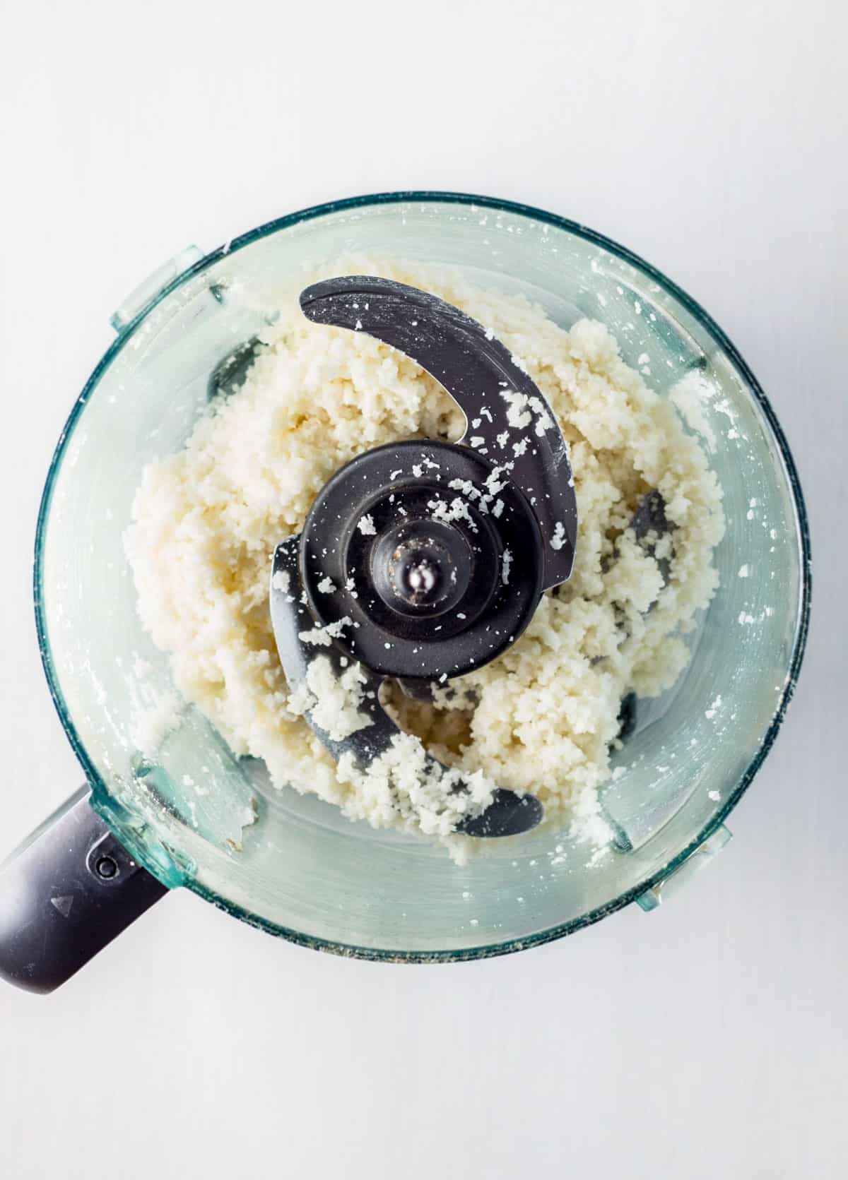 Shredded coconut partially blended in a food processor.