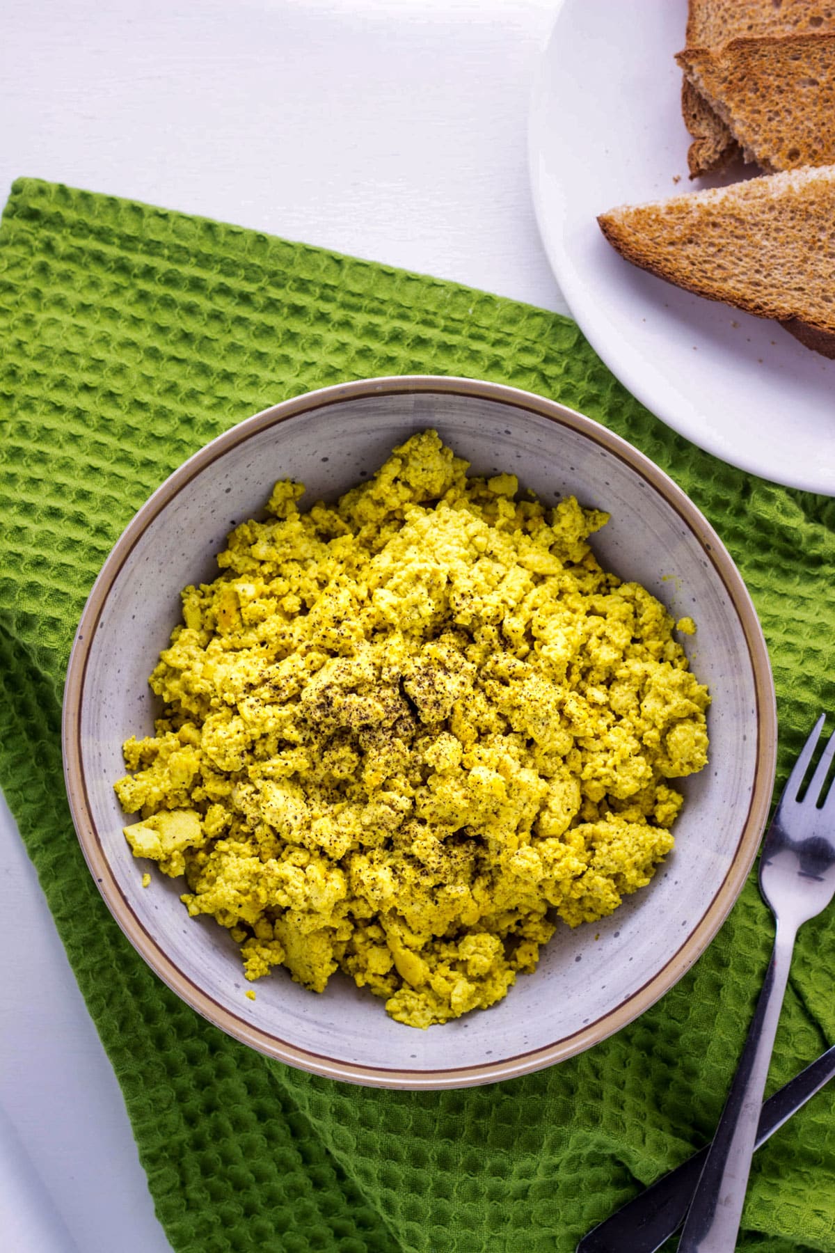 A bowl of Basic Tofu Scramble sitting on a green towel.