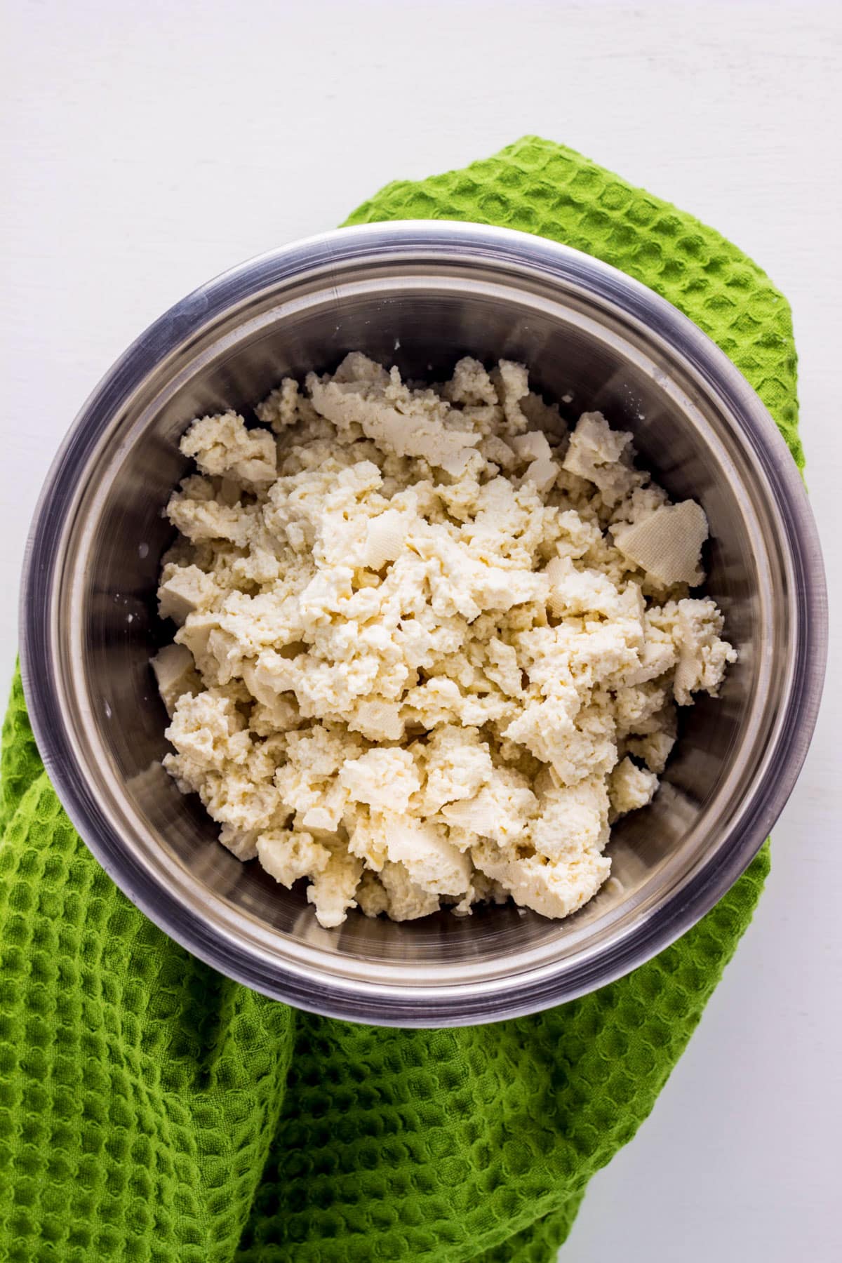 A bowl of plain tofu crumbled into small pieces to make a Basic Tofu Scramble.
