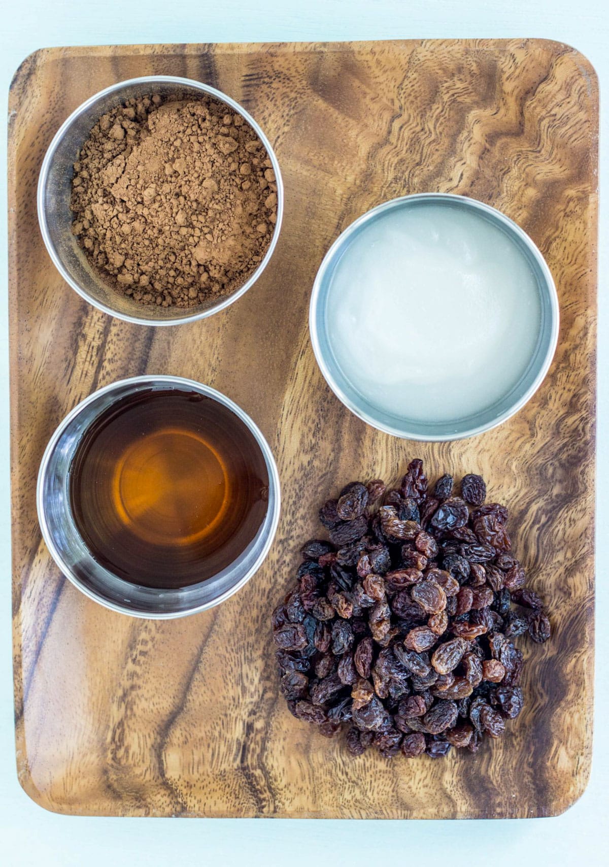 The ingredients needed to make Vegan Chocolate Covered Raisins - raisins, maple syrup, coconut oil and cocoa powder.