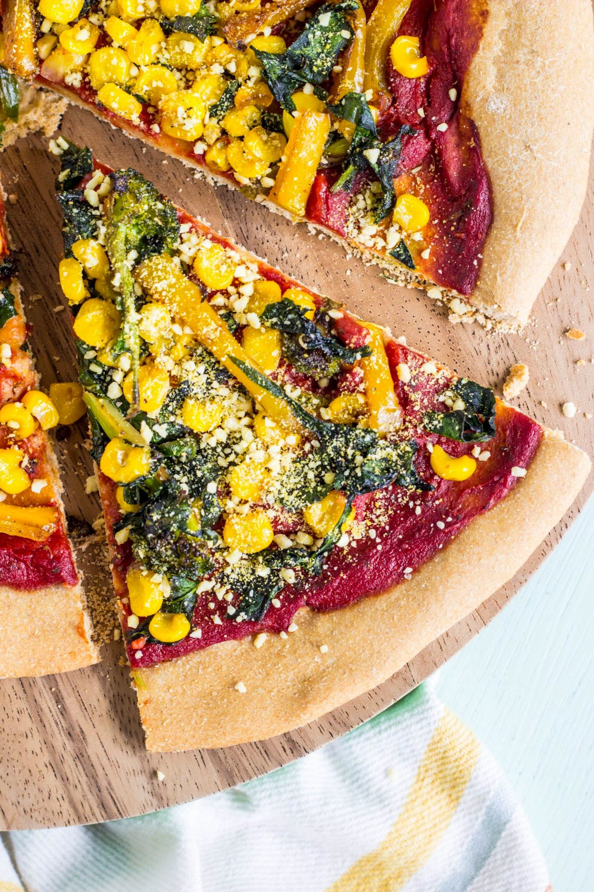 Overhead close up of a slice of Yeast Free Pizza Crust with sauce, vegetables and cashew parmesan.