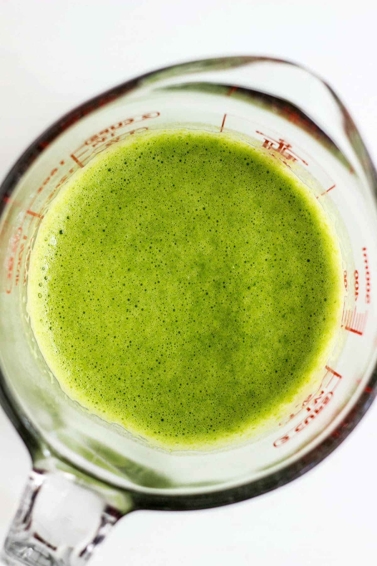Overhead shot of a measuring cup filled with green liquid.