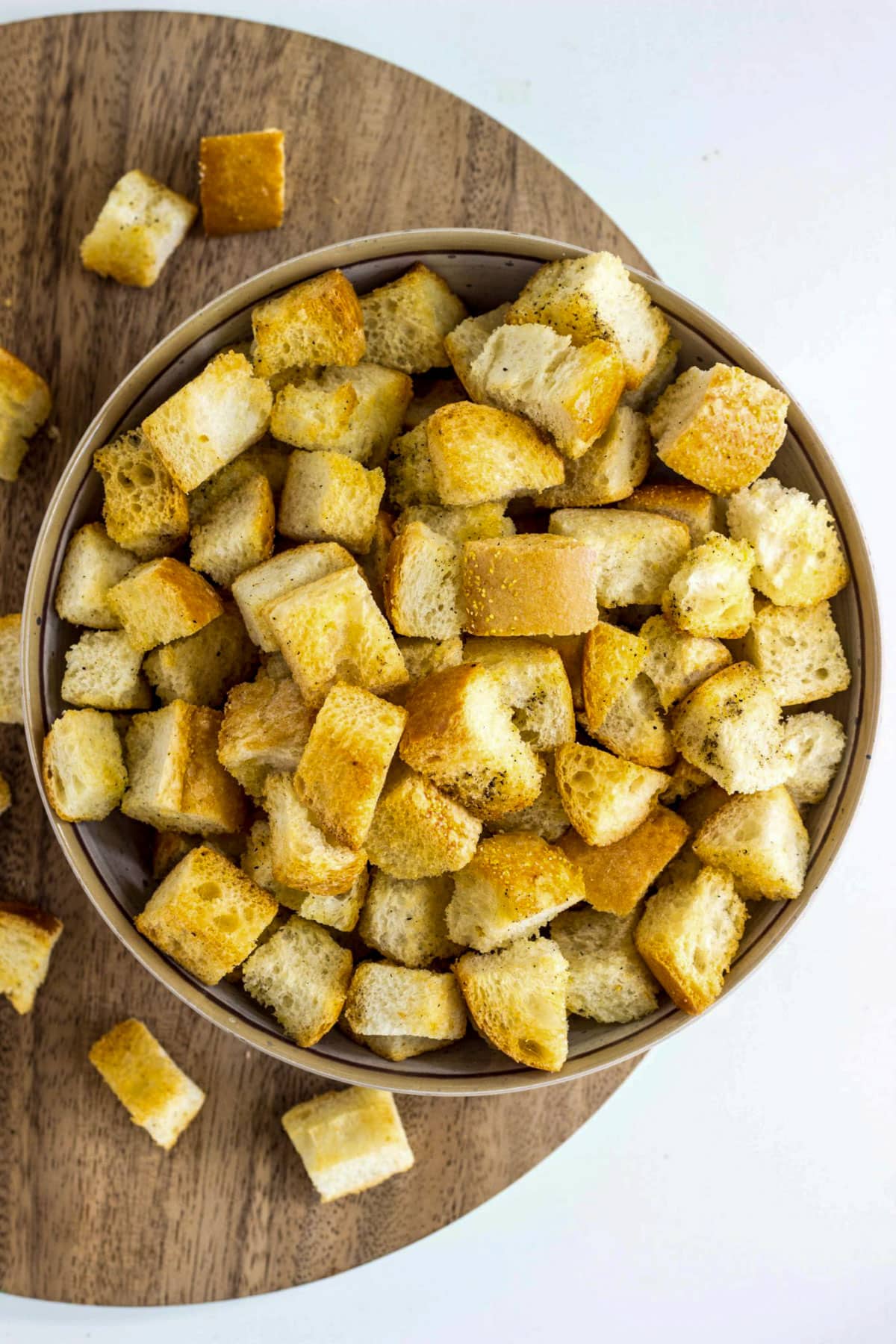 A bowl of Simple Vegan Croutons sitting on a wooden board.