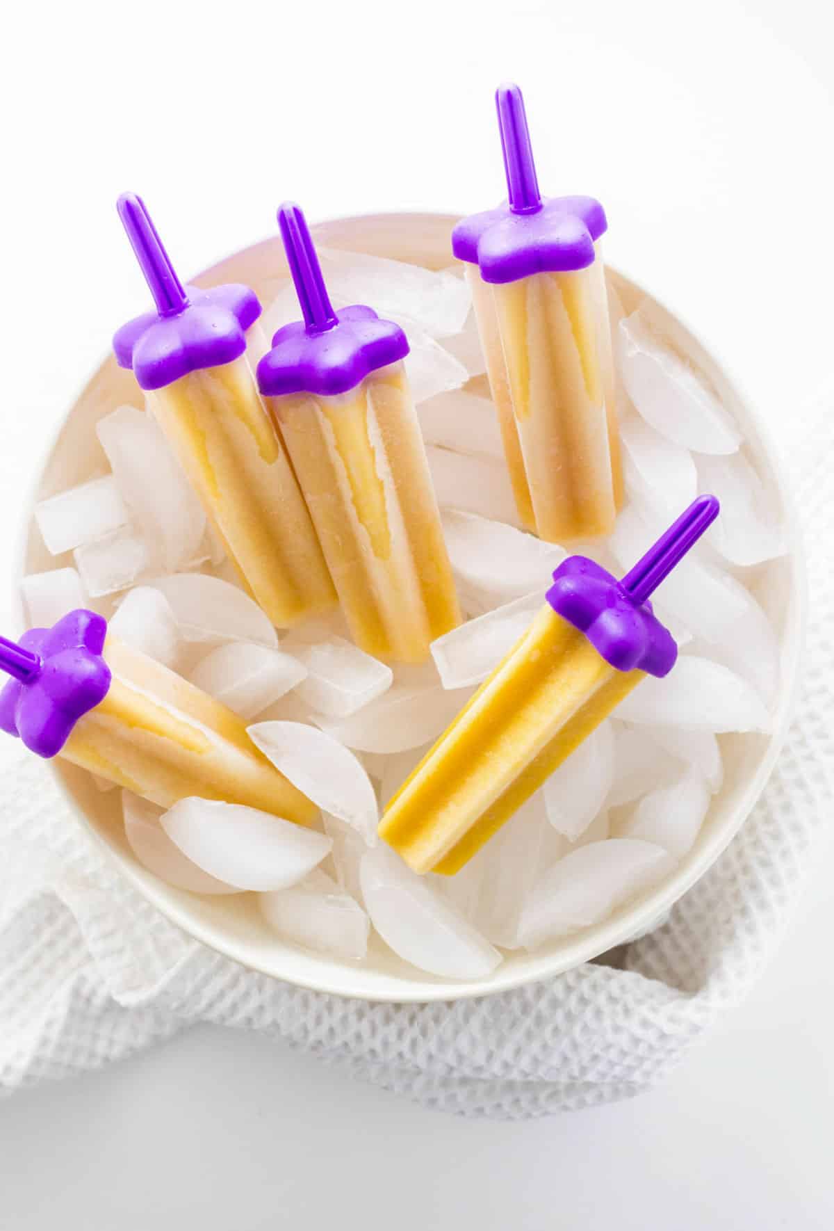 Overhead view of Vegan Cantaloupe Popsicles in a large bowl filled with ice.