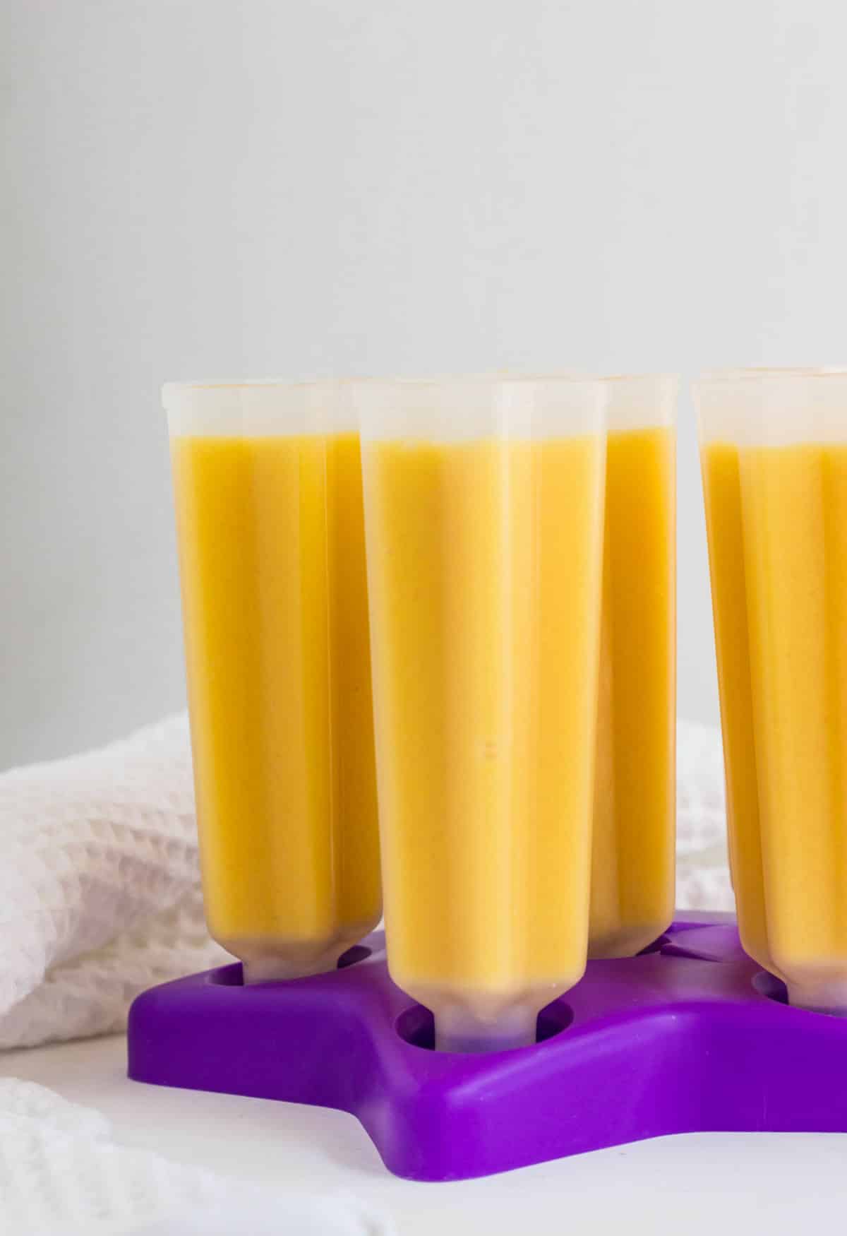 Side view of popsicle molds filled with cantaloupe molds before freezing.