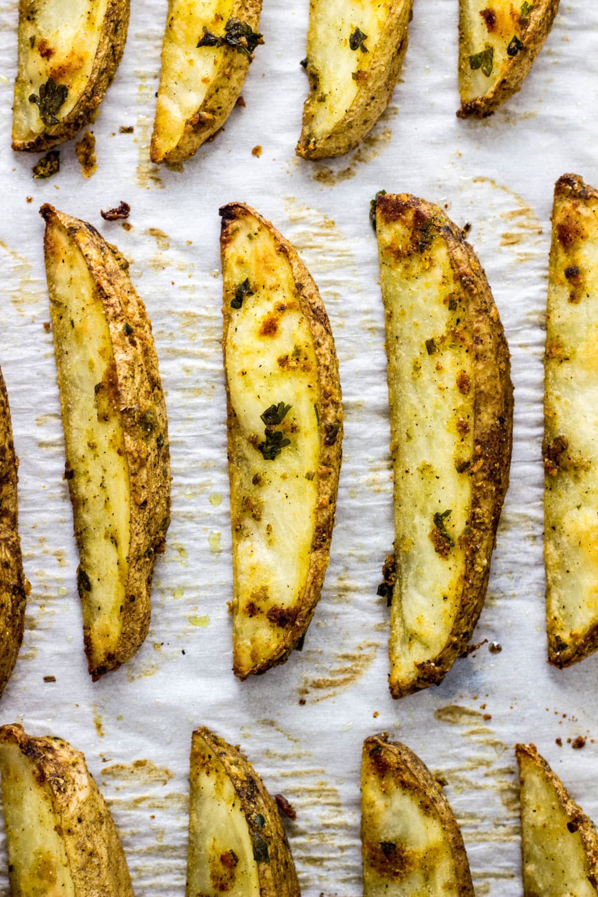 Baked Vegan Cheese Herb Potato Wedges on a baking sheet lined with parchment paper.