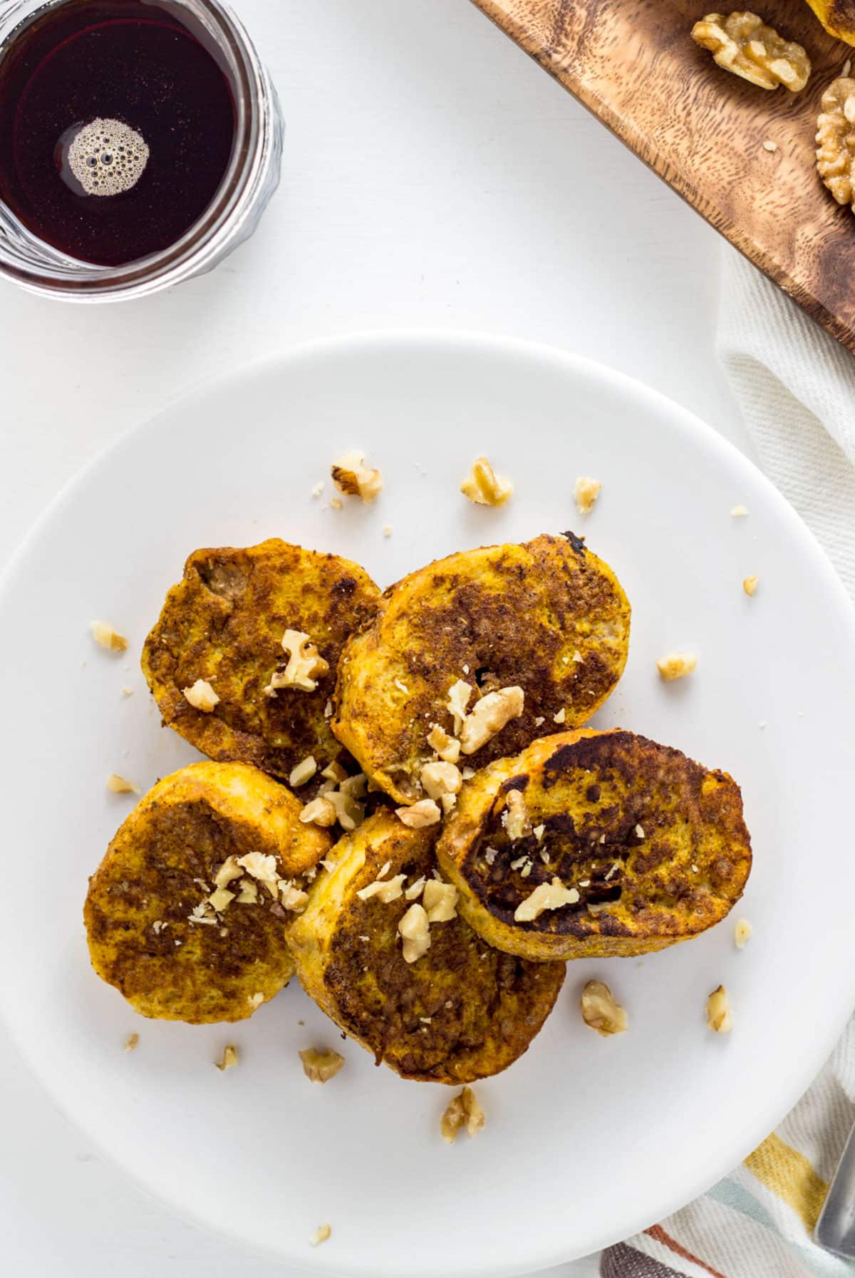 Pumpkin Chia French Toast on a small white plate with chopped walnuts scattered over the top.
