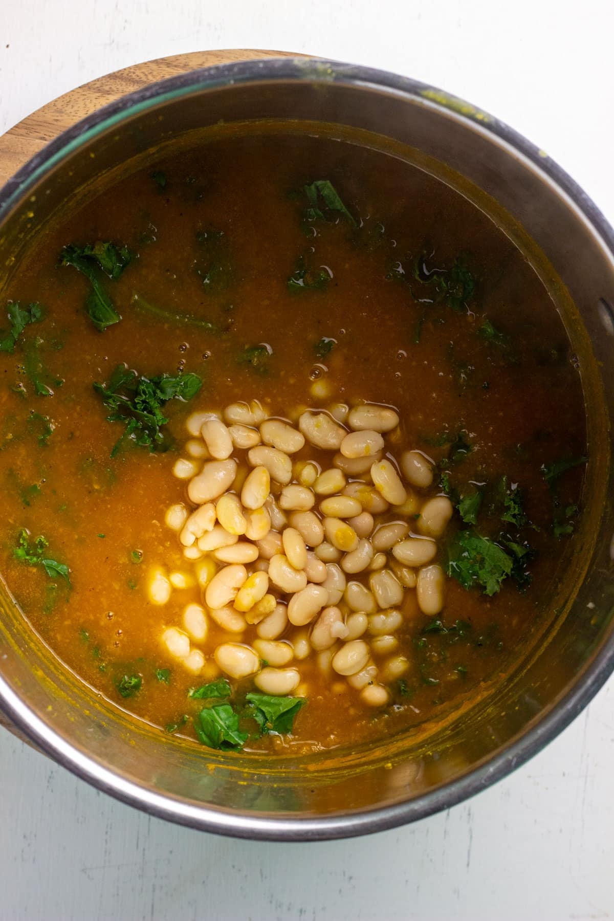 Close up of a pot of pureed kabocha with white beans and kale.