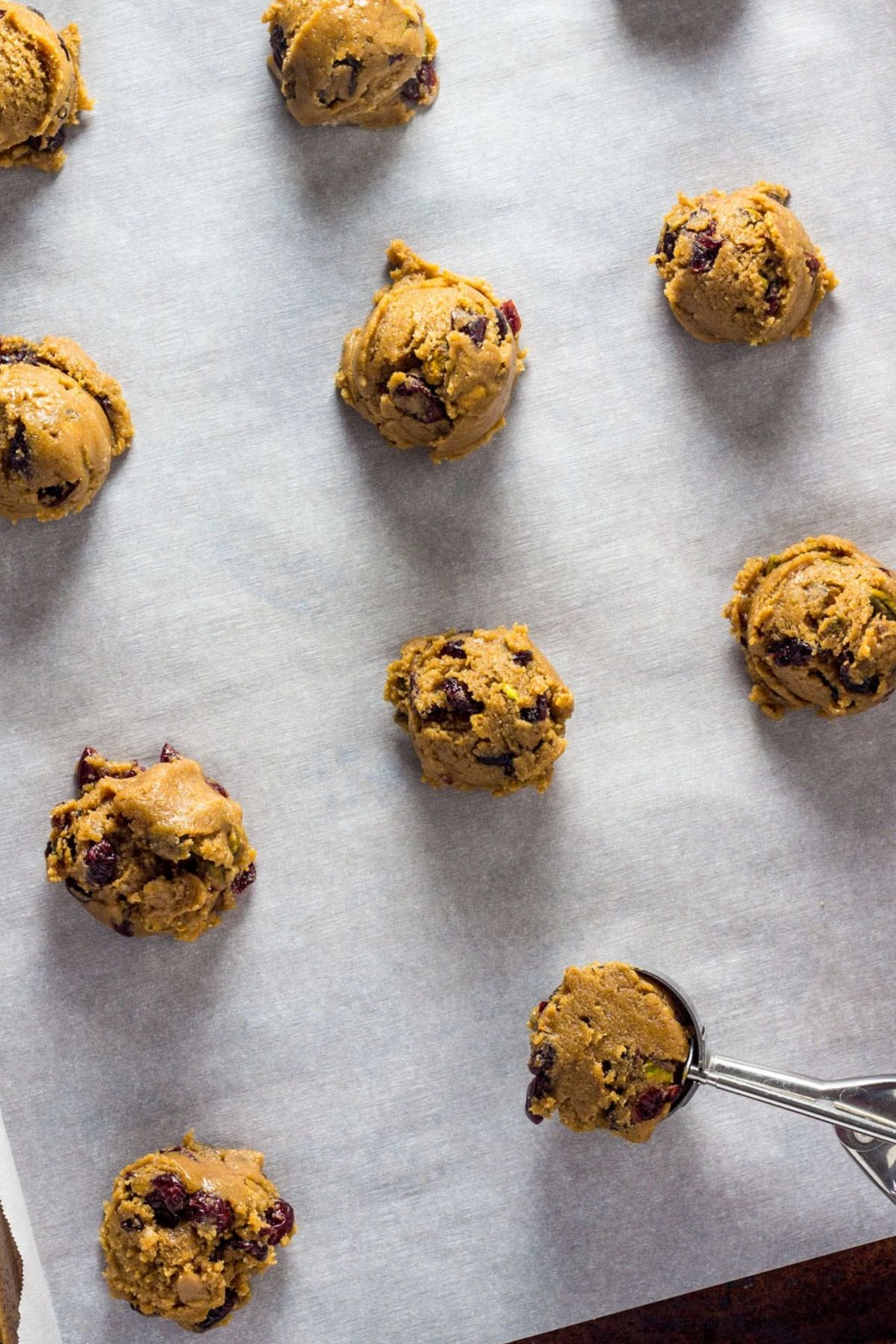 Overhead view of scoops of cookie dough on a baking sheet lined with parchment paper.