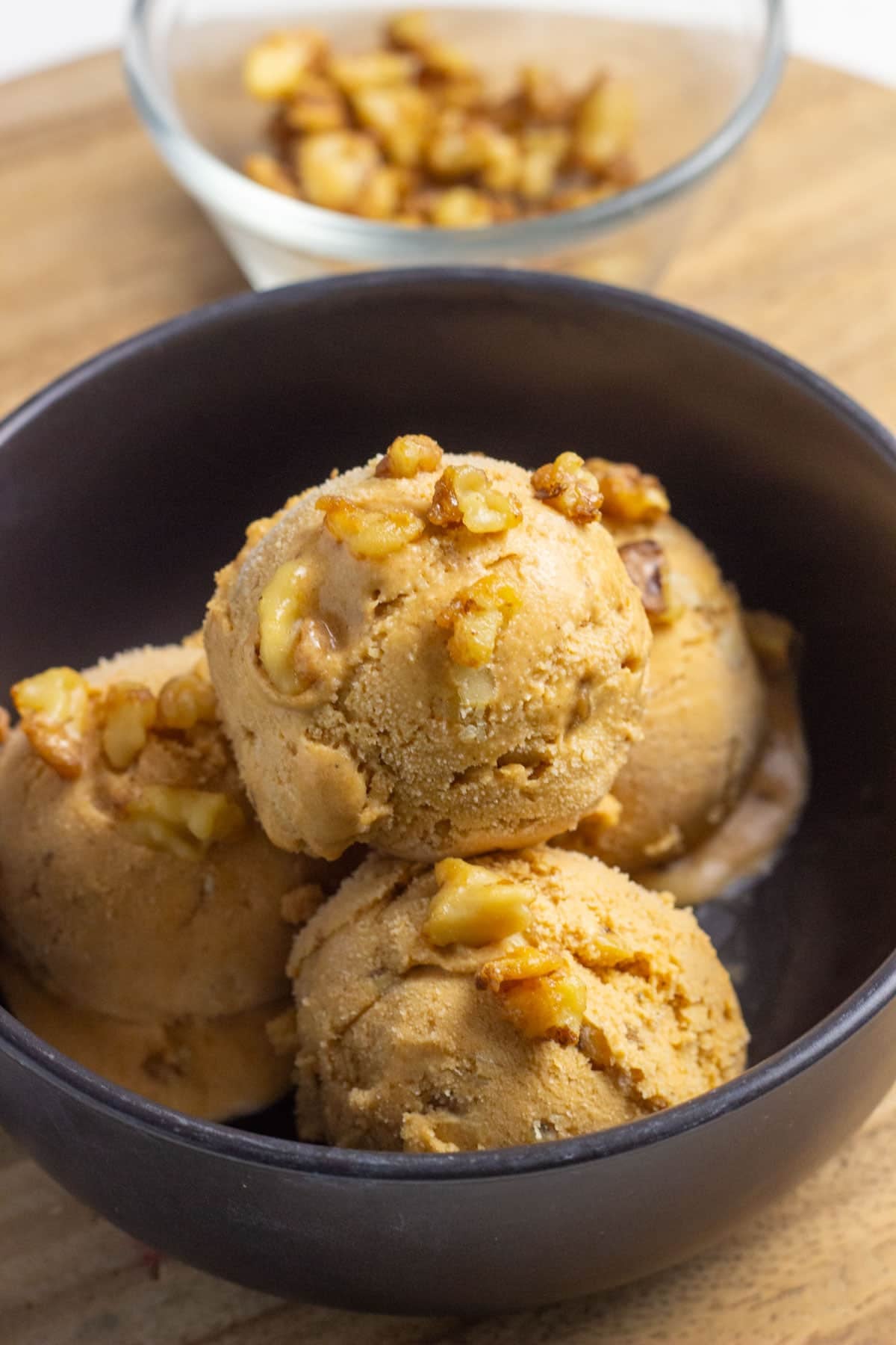 Close up of a bowl of Vegan Pumpkin Ice Cream with candied walnuts sprinkled on top.